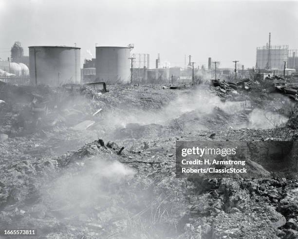 1960s Air and ground pollution burning refuse dump in an industrial area.