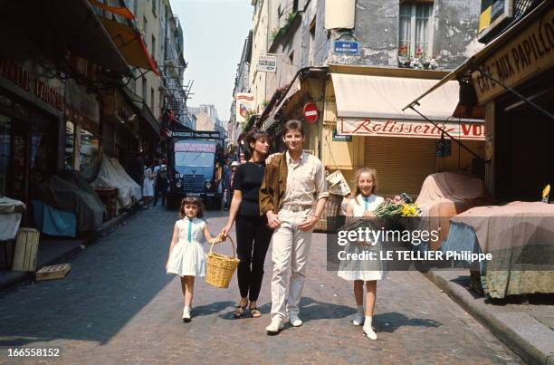 Close Up Hugues Aufray. Hugues AUFRAY dans la rue Mouffetard avec son épouse Hélène et leurs deux filles Marie et Charlotte, en juillet 1964.