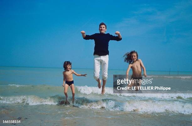 Close Up Hugues Aufray. Hugues AUFRAY en vacances à la mer en Normandie avec ses deux filles Marie et Charlotte, sautant dans les vagues, en juillet...