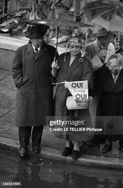 Official Visit Of General Charles De Gaulle To Strasbourg. A Strasbourg, dans une rue, parmi un groupe de personnes sous des parapluies, une femme,...