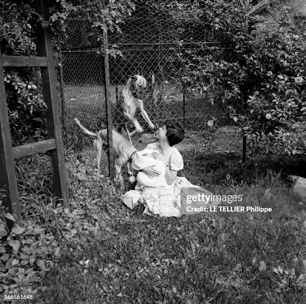 Close-Up Of Cecile Aubry And Son Mehdi. En France, en juin 1956, portrait de Cécile AUBRY les cheveux courts, assise sur l'herbe dans un jardin,...