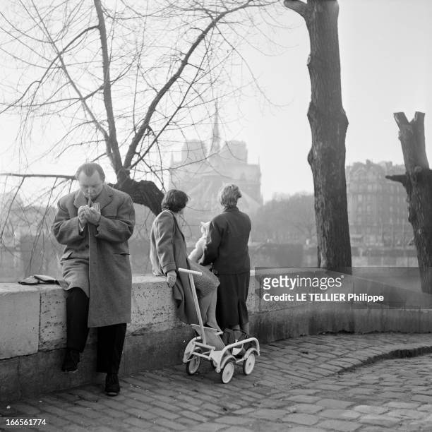 Hans Hellmut Kirst In Paris. Paris - 15 mars 1955 - L'écrivain Hans Hellmut KIRST assis sur le muret d'un quai de la Seine, allumant un cigare, à...