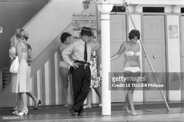 The Deligny Pool In Paris. Paris, le 8 juillet 1959, piscine Deligny, scènes de bains. Devant les cabines et les baigneuses, appuyé contre un pylone,...