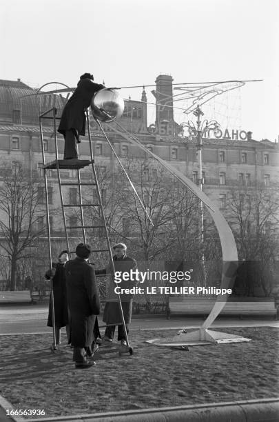 Moscow Winter. A Moscou, le 16 Novembre 1959, reportage sur la ville: un Moscovite, monté au sommet d'un escabeau sur roulettes maintenu par trois...