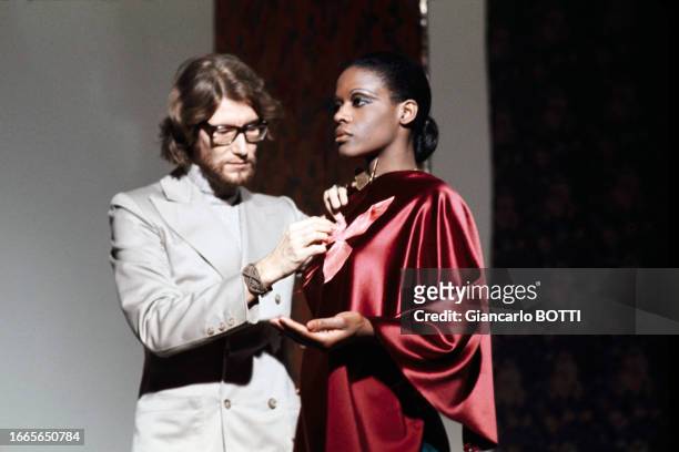 Yves Saint Laurent préparant la tenue de Lisette Malidor dans les coulisses de l'émission Show Roland Petit à Paris en décembre 1970