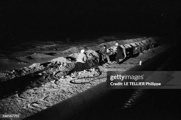 Construction Of Pipe Line. En 1958, dans le désert du Sahara, des d'ouvriers, travaillant de nuit avec des marteaux piqueurs près d'une section de...