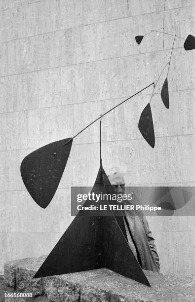 Sculptor Alexander Calder Makes A Mobile For The Palace Of Unesco. A Paris, devant le palais de l'UNESCO, Alexandre CALDER, en imperméable, posant...