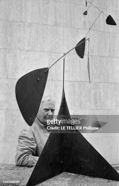 Sculptor Alexander Calder Makes A Mobile For The Palace Of Unesco. A Paris, devant le palais de l'UNESCO, Alexandre CALDER, en imperméable, posant...