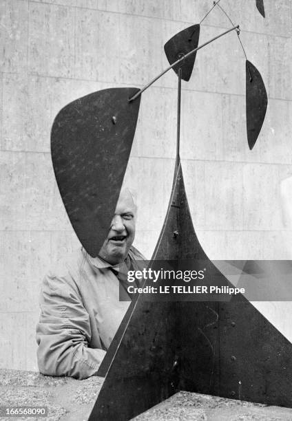 Sculptor Alexander Calder Makes A Mobile For The Palace Of Unesco. A Paris, devant le palais de l'UNESCO, Alexandre CALDER, en imperméable, posant...