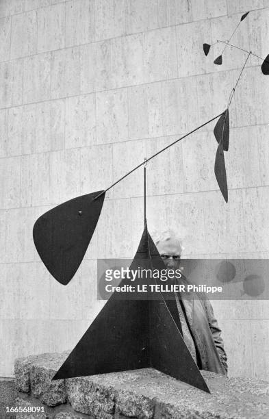 Sculptor Alexander Calder Makes A Mobile For The Palace Of Unesco. A Paris, devant le palais de l'UNESCO, Alexandre CALDER, en imperméable, posant...