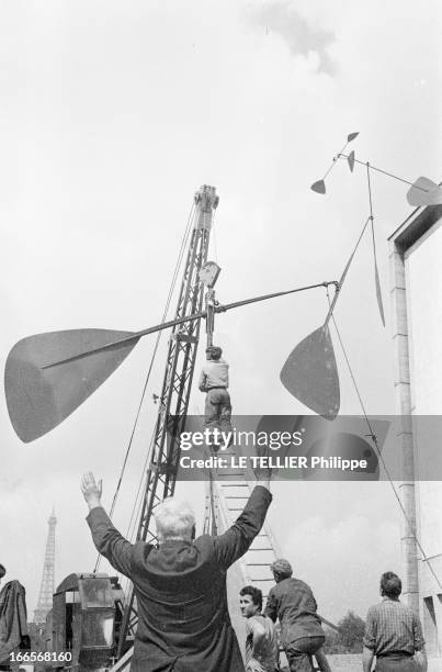 Sculptor Alexander Calder Makes A Mobile For The Palace Of Unesco. A Paris, devant le palais de l'UNESCO, Alexandre CALDER, de dos, les bras levés,...