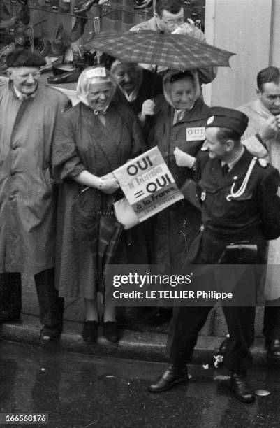 Official Visit Of General Charles De Gaulle To Strasbourg. A Strasbourg, dans une rue, derrière un soldat en uniforme, deux femmes sous un parapluie,...
