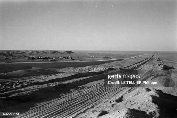 Construction Of Pipe Line. En 1958, dans le désert du Sahara, piste, bordée de tente et de camions, sur la trajectoire du pipeline construit pour...