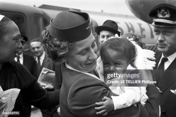 Josephine Baker Adopts A Tenth Child. En France, le 25 avril 1959, sur la piste d'un aéroport, une hôtesse de l'air tient dans ses bras Mara, le 10e...