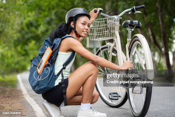 african american woman using solar panels to charge electrical devices and using a bicycle to travel, clean energy concept, alternative energy, energy saving. - mississauga stock pictures, royalty-free photos & images