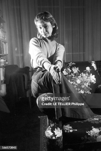 Evelyne Ker And Marianne Lecene. Paris- période 1954, 1955- Chez elle, Evelyne KER, actrice française, assise sur l'accoudoir d'un canapé à motifs...