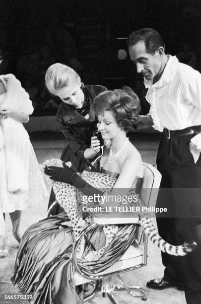 At The Antonio Circus. Paris- 7 Octobre 1959- Au cirque ANTONIO, le Coiffeur coiffant une jeune femme en robe longue à bustier assise sur un fauteuil...