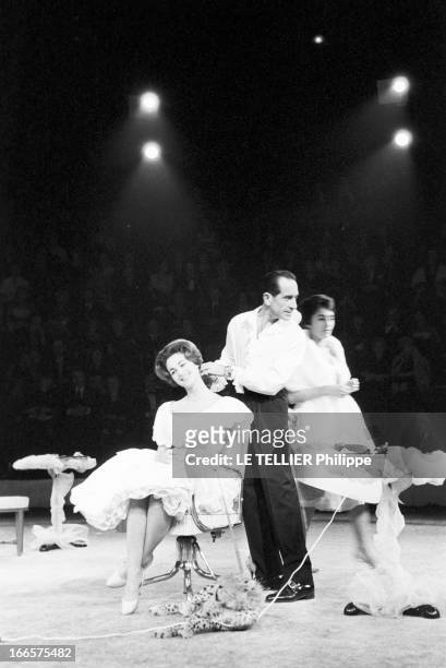 At The Antonio Circus. Paris- 7 Octobre 1959- Au cirque ANTONIO, le Coiffeur coiffant une jeune femme en robe blanche à volants, assise sur un...