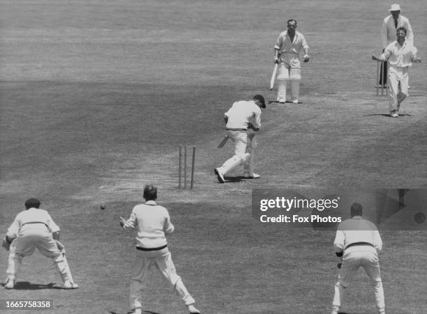 England batsman Peter May is bowled out for 104 runs by Ray Lindwall of Australia, as May's batting partner Bill Edrich looks on, during England's...