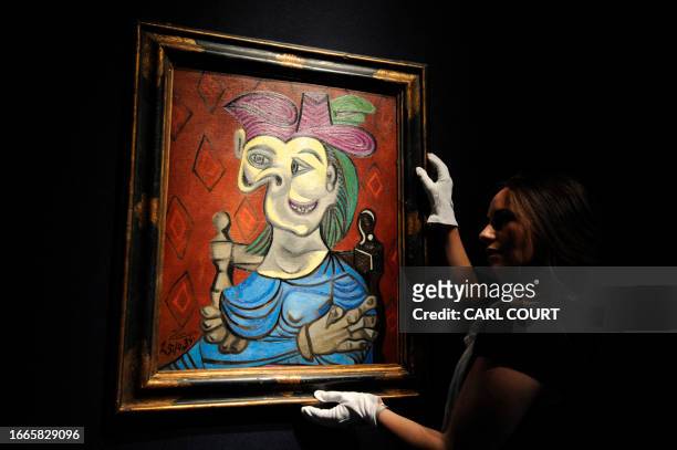 Christie's employee poses with a painting entitled 'Femme assise, robe bleue' by Spanish artist Pablo Picasso at Christie's auction house in central...