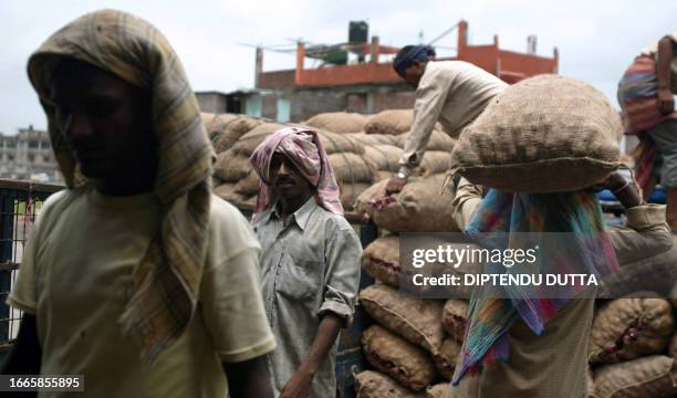 Indian labourers load potatoes and onions in a truck at a regulated market in Siliguri on June 21, 2008. Indian inflation raced to its highest level...