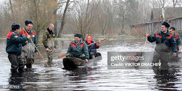 Belarus Emergencies Ministry officers look at a woman paddling on a boat during spring flood in the Belarus village of Khvoensk, some 280 km south of...