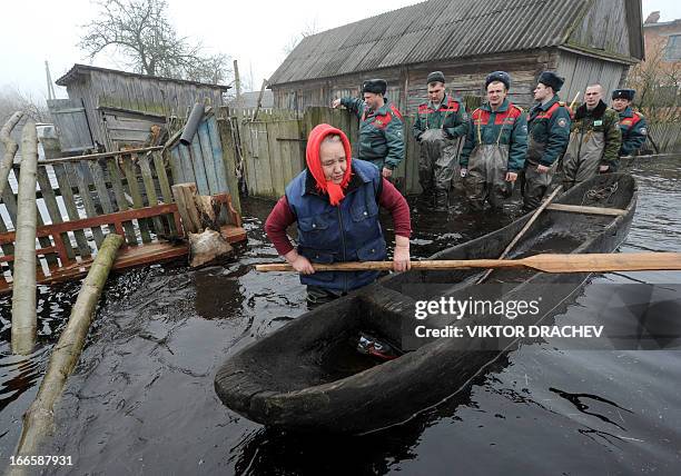 Belarus Emergencies Ministry officers look at a woman as she prepares to paddle on a boat during spring flood in the Belarus village of Khvoensk,...