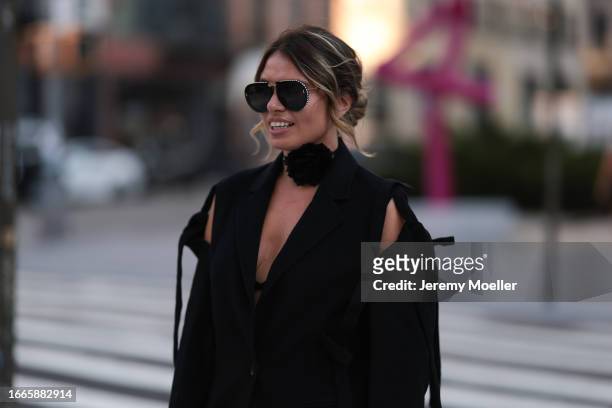 Natalia Levsina seen wearing black rhinestones pattern sunglasses, black flower necklace, JNBY Official black blazer jacket with cut-outs and straps,...