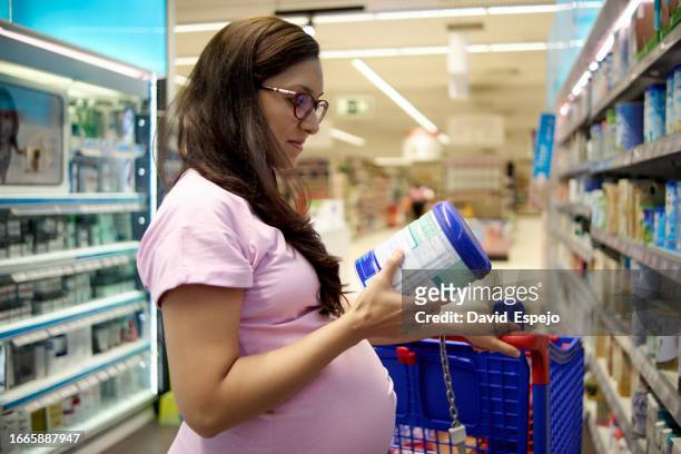 pregnant woman buying baby formula milk at the supermarket. - mom buying milk stock-fotos und bilder
