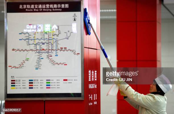 Worker cleans the map of subway lines on the platform of the newly-opened subway line in Beijing on December 30, 2010. Beijing opens five new subway...