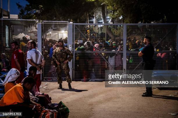 Migrants stand behind the fences of the operational center called "Hotspot" on the Italian island of Lampedusa on September 14, 2023. The tiny...