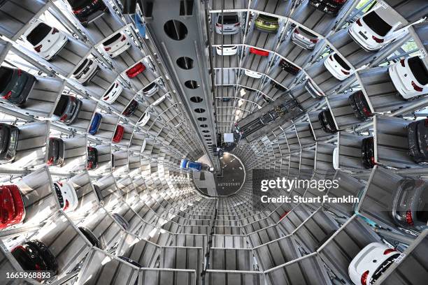 Volkswagen cars stand on elevator platforms inside one of the twin towers used as storage at the Autostadt promotional facility next to the...