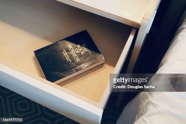 motel end table with a copy of the book of mormon - bureau de change - fotografias e filmes do acervo