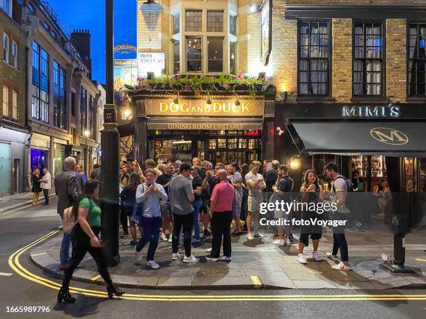 london nightlife drinkers on pavement outside popular traditional pub in soho - london pub stock pictures, royalty-free photos & images