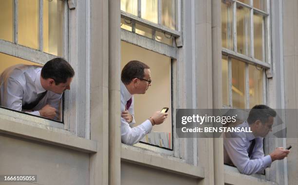 City workers look down from office windows at student protesters marching in the street against cuts in higher education funding in London on...
