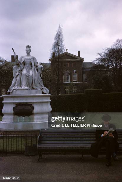 The Residence Of The Princess Margaret Of England. Un homme lisant sur un banc, devant une statue de reine dans un parc devant la résidence de la...