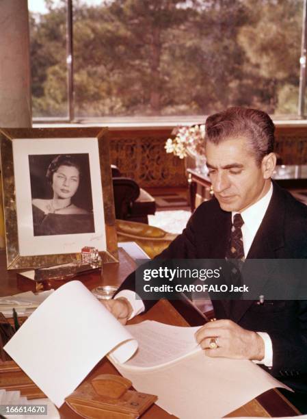 Rendezvous With The Shah Of Iran. Portrait du Shah d'Iran, veste noire sur chemise blanche et cravate, assis à son bureau et feuilletant des...