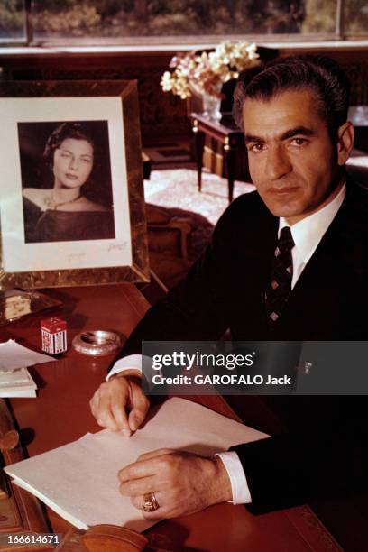 Rendezvous With The Shah Of Iran. Portrait du Shah d'Iran, veste noire sur chemise blanche et cravate, souriant, assis à son bureau, mains posées sur...