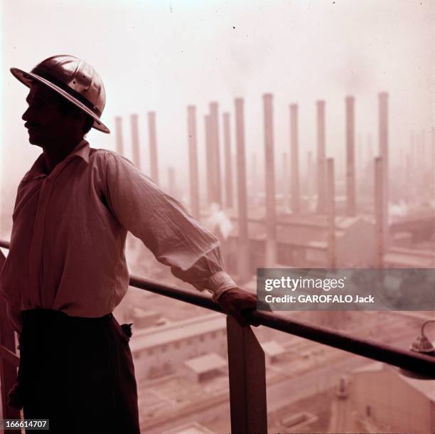 Abadan Refinery In Iran. Abadan - fin des années 50 - Un ouvrier portant un casque de protection, posant devant les cheminées d'une raffinerie de...