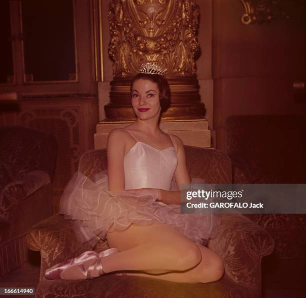 Christine Bourrillot, Dancer. Devant colonne dorée sculptée, portant un tutu et un diadème, la danseuse Christine BOURRILLOT souriante, assise jambes...