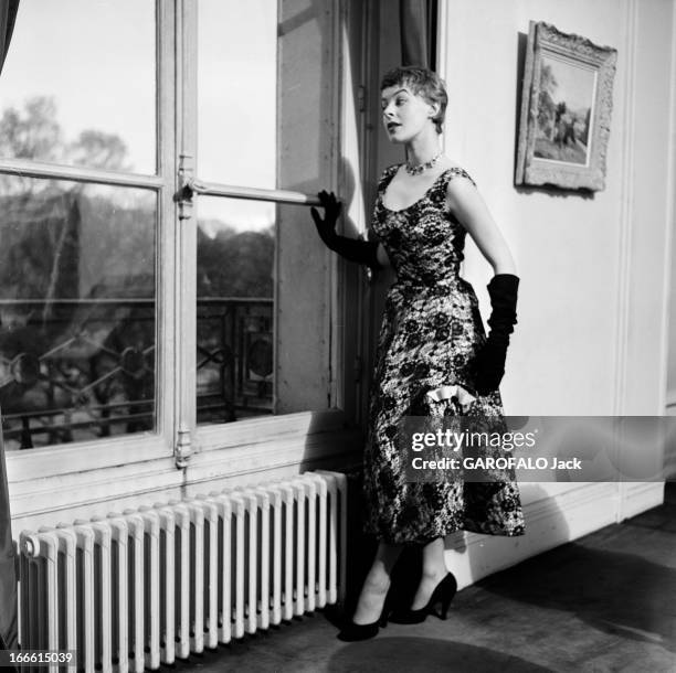 Fashion At Germaine Lecomte. Une femme mannequin portant une robe de soirée Germaine Lecomte, longue, avec un décolleté, des gants, debout devant une...
