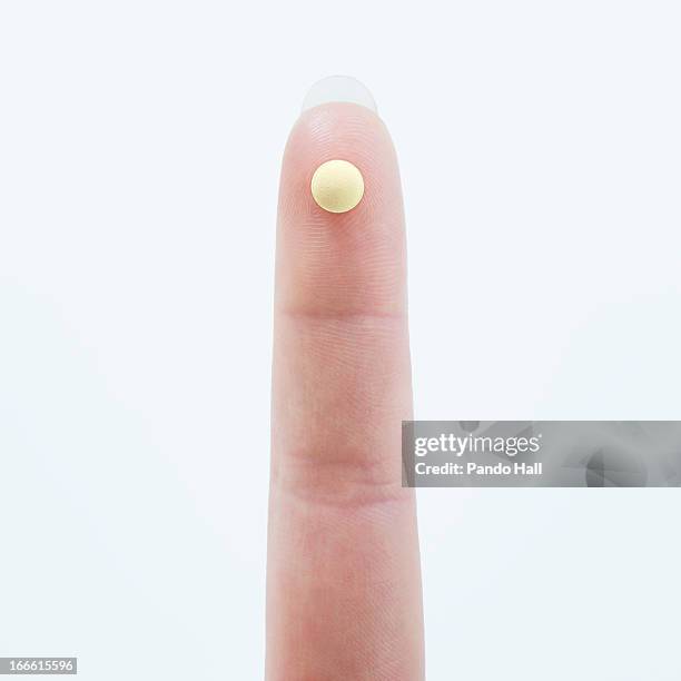 woman's finger with birth control pill - antibabypille stock-fotos und bilder