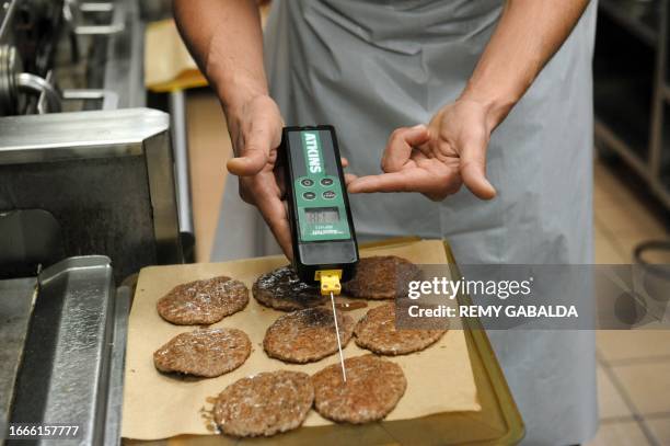 An employee uses a temperature sensor to check the split level of hamburgers at a US fast food Mac Donalds fast food restaurant on December 1, 2011...