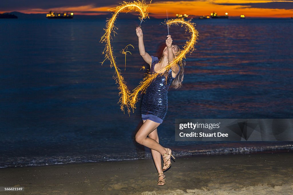 Woman with sparklers at beach