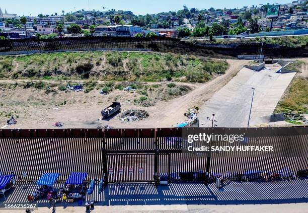 This aerial picture taken on September 14, 2023 shows the US-Mexico border fence with camp shelters left by migrants in San Ysidro, California, on...