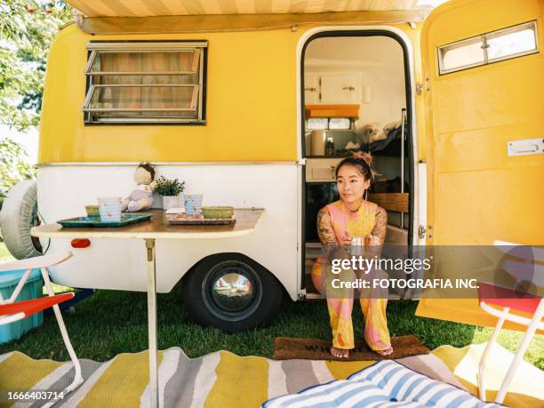 mid adult asian woman enjoying trailer camping in summer - caravan stockfoto's en -beelden