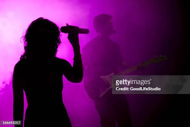 silhouette of female holding microphone in purple light - zangeres stockfoto's en -beelden