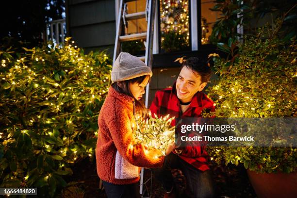 medium shot girl holding lights while decorating home for christmas - espírito natalino imagens e fotografias de stock