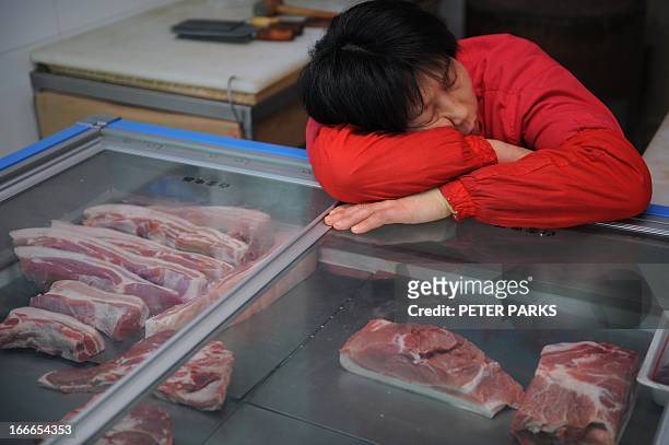 Pork seller takes a nap in a wet market in Shanghai on April 15, 2013. China's economic growth slowed to 7.7 percent in the first quarter, data...