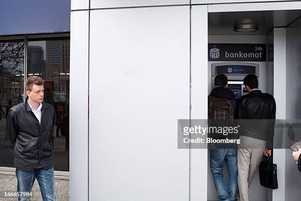 Customers use an automated teller machine operated by PKO Bank Polski SA in Warsaw, Poland, on Thursday, April 11, 2013. Poland's central bank kept...